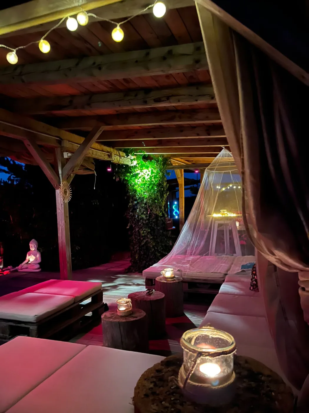 Chill-Lounge mit Kerzenlicht, Betten und Buddha im Garten Eden